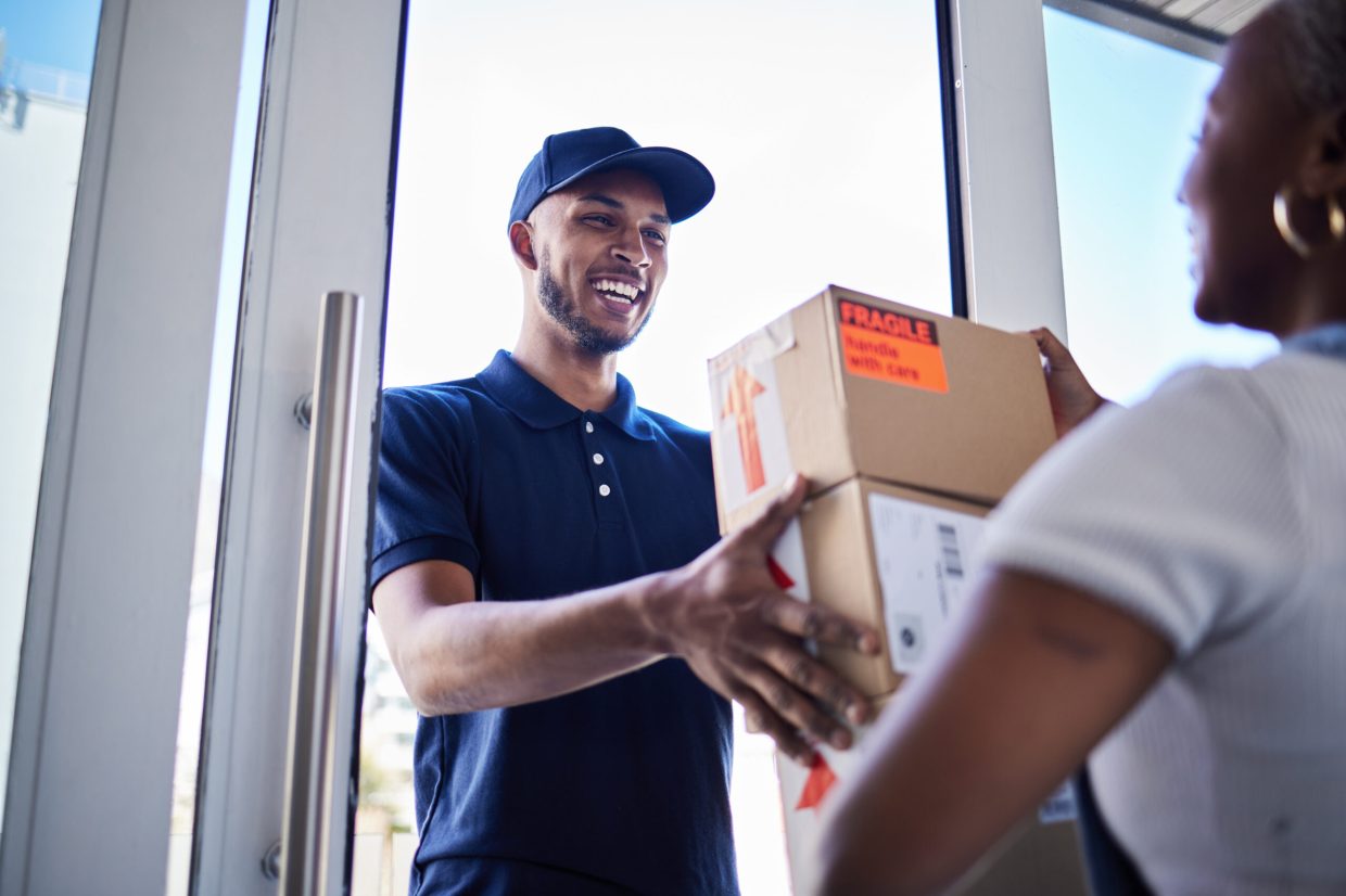 Ecommerce, happy delivery man with box and woman at her front door. Online shopping or logistics, supply chain or distribution and African female person receive her cardboard parcel with smile.