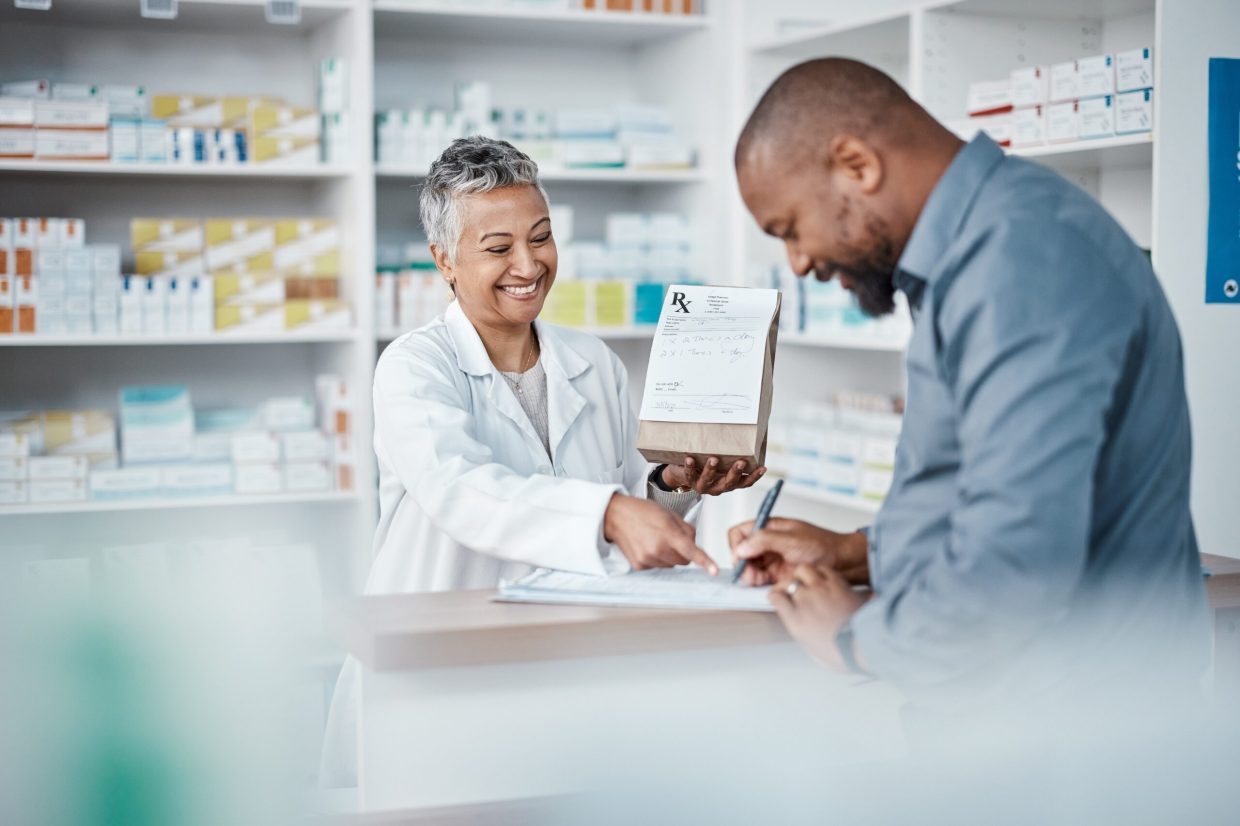 Medicine, shopping or pharmacist with customer writing personal or medical information in pharmacy. Consulting, pills or happy senior doctor helping or speaking to black man or sick African customer.